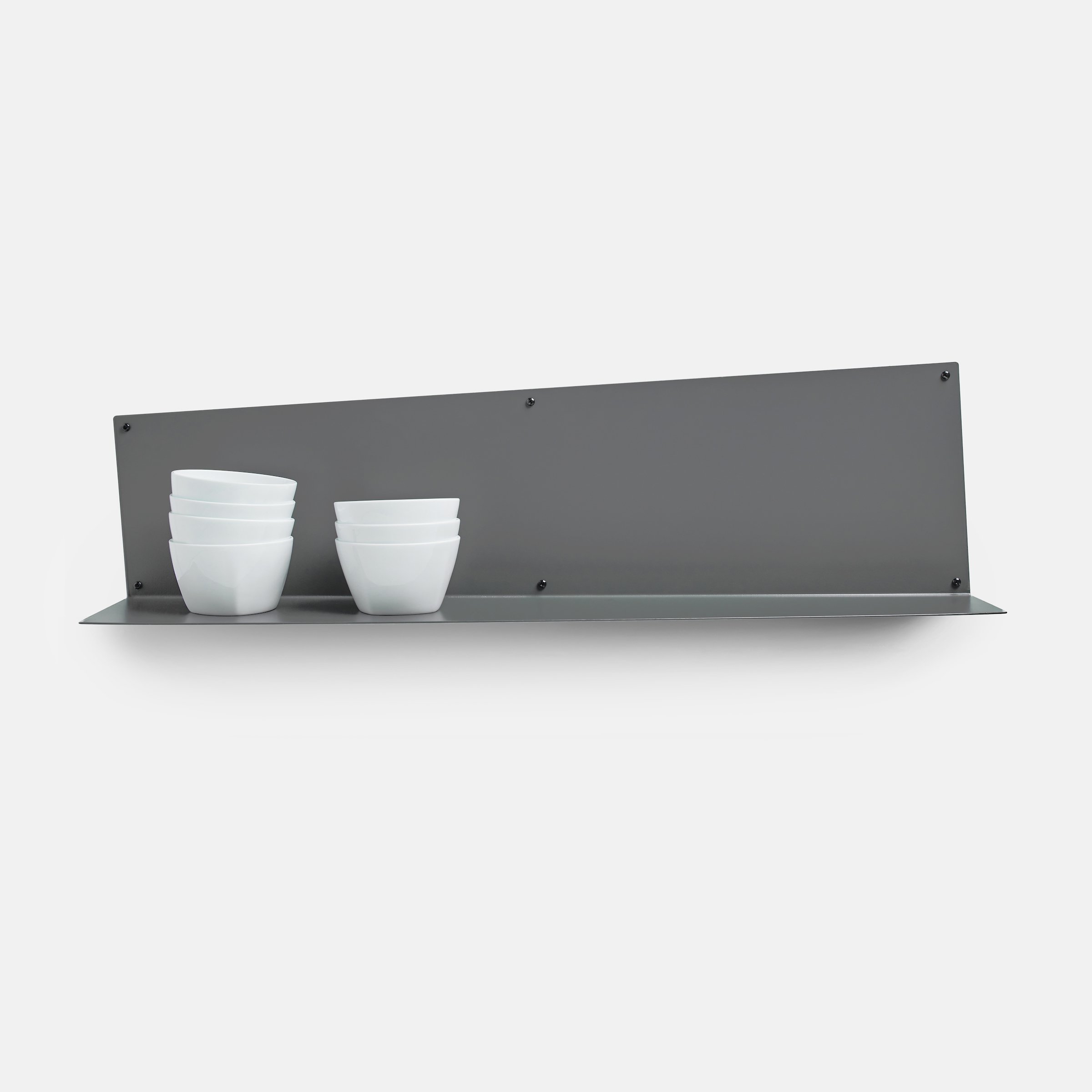Metal wall shelf with stacked white bowls on a white background