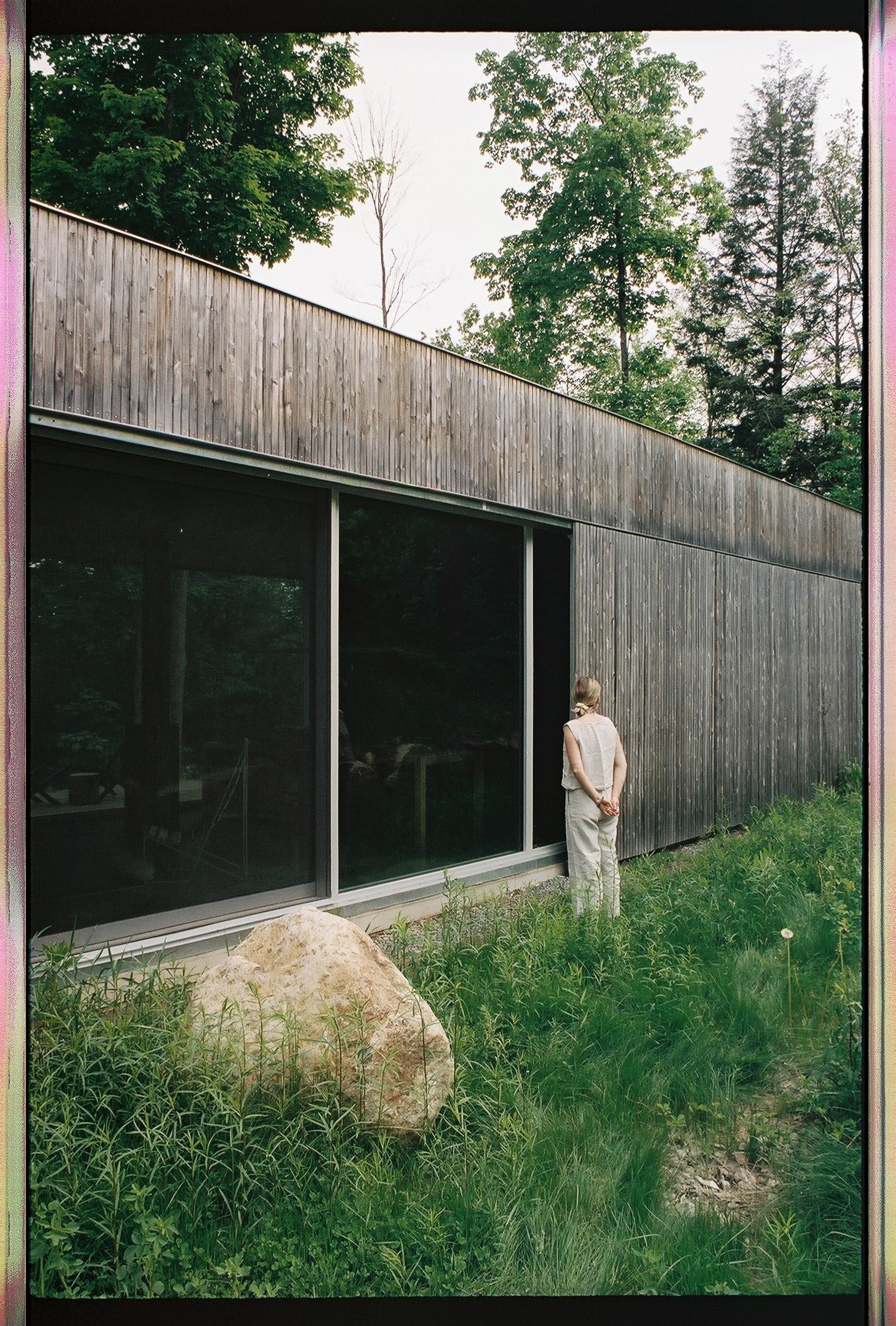 an artist standing outside a hinter space, surrounded by grass and trees